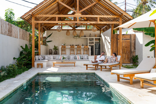 Young couple enjoying summer vacation at a beautiful bali style private villa with swimming pool