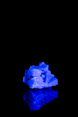 Naklejka premium Fluorescent fluorite crystal under UV light on black background with reflection
