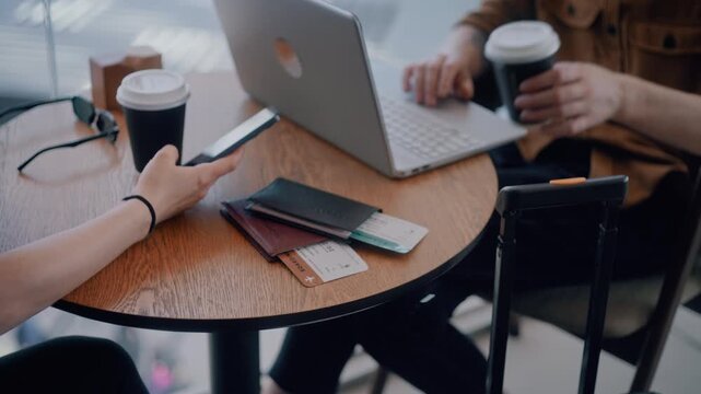 Close-up of People drinking coffee and using devices while waiting for their flight in an airport terminal