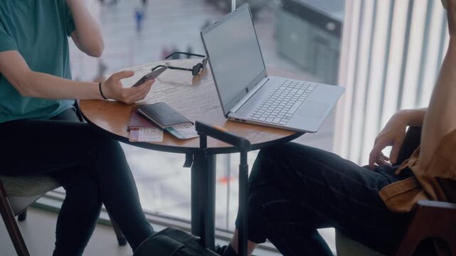 Unrecognizable people drinking coffee and using devices while waiting at the airport departure lounge