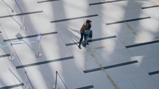 High-angle view of a happy couple emotionally reuniting and embracing in a sunlit airport terminal