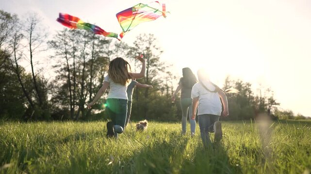 Child in red cape plays superhero in field at sunset. Girl runs across grass with fist raised. Kid in mask imagines flight. Superhero child enjoys freedom. Happy childhood fantasy in nature.