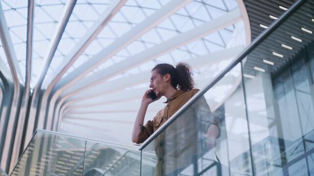 A young executive uses a layover or waiting moment to make a call while positioned on the airport stairs. 