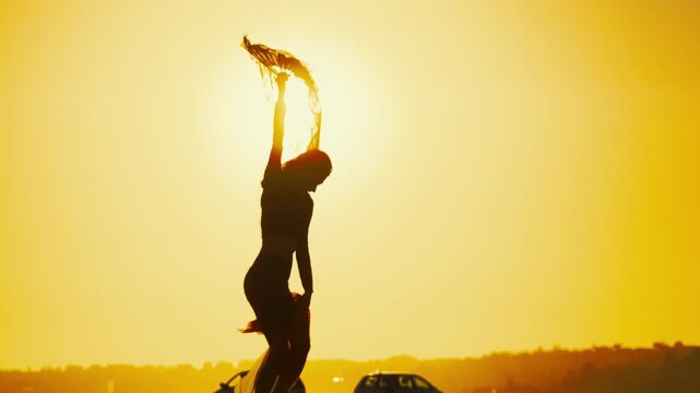 Dancer twirls with a scarf during sunset by the road in a bright sky at an evening outdoor event