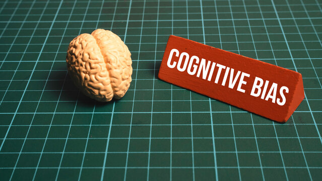 Model of human brain next to cognitive bias sign on green grid background for psychology and behavior