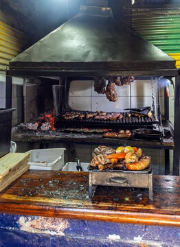 Traditional Argentine Parrilla Barbecue with Assorted Meats Grilling over Hot Charcoal Embers in a Rustic Restaurant