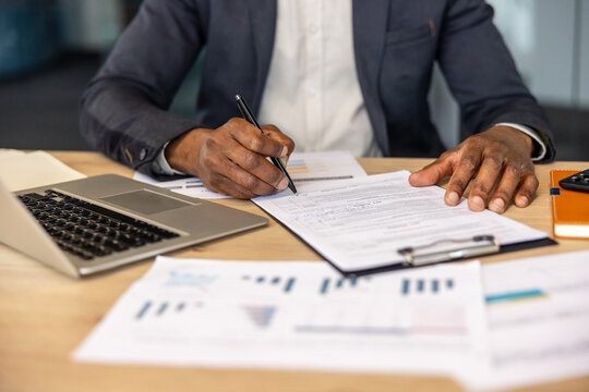 Entrepreneur signing a business contract, focusing on legal paperwork at a modern office desk with a laptop and financial documents, symbolizing agreement, success, and official procedures