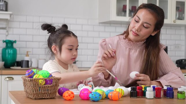 Asian mother and little daughter painting colorful easter eggs with brush at kitchen, Happy family spring holiday celebration, childhood creative art craft learning, motherhood childcare, easter day