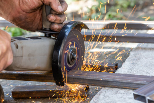 Close-up of angle grinder cutting metal bars outdoors