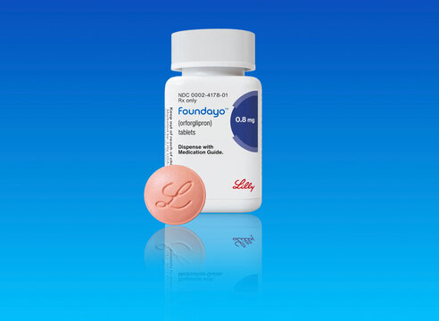Studio shot of bottle of foundayo weight loss drug  with pill from Eli Lilly on blue background with copy space. Copenhagen, Denmark - May 1, 2026.