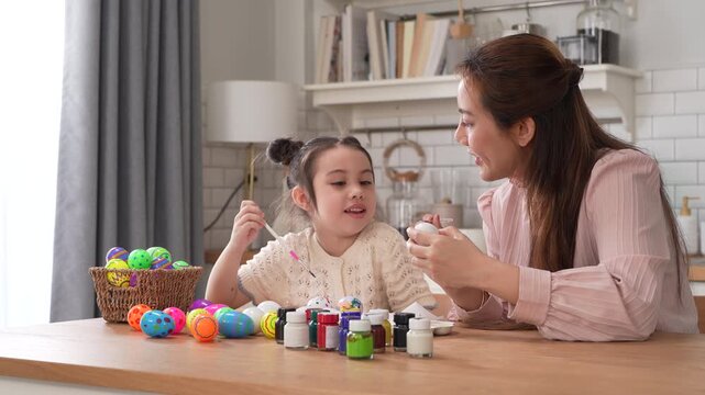 Asian mother and little daughter painting colorful easter eggs with brush at kitchen, Happy family spring holiday celebration, childhood creative art craft learning, motherhood childcare, easter day