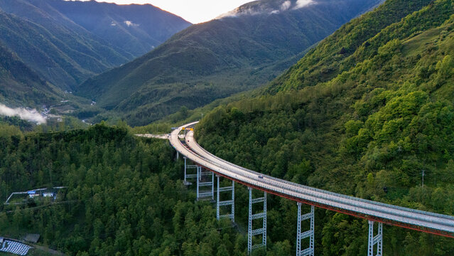 Aerial view of YaXi Highway's iconic double spiral tunnel winding through lush green mountains in Sichuan, China