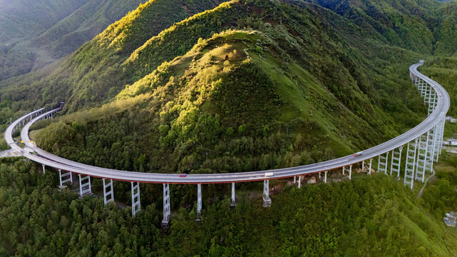 Aerial view of YaXi Highway's iconic double spiral tunnel winding through lush green mountains in Sichuan, China