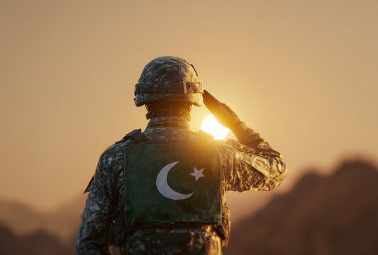 a pakistani soldier saluting in front of an pakistani flag with the sun setting behind them.