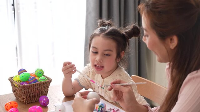 Asian mother and little daughter painting colorful easter eggs with brush at kitchen, Happy family spring holiday celebration, childhood creative art craft learning, motherhood childcare, easter day