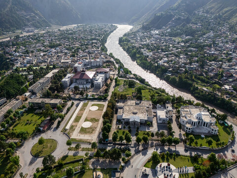 Aerial view of the urban landscape and winding river surrounded by lush green hills and mountains in Muzaffarabad, Azad Kashmir, Pakistan.