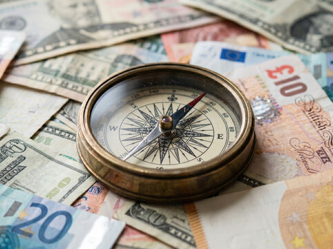 Brass compass lying on US dollars and other currency