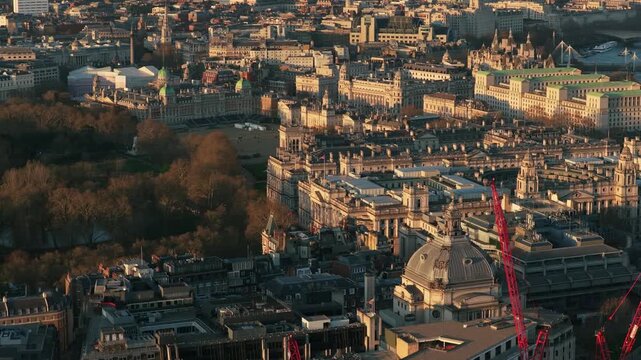 Grand buildings and parks in Central London revealing Buckingham Palace, Ritz London hotel, and Green Park during a glowing sunset with cranes developing the city