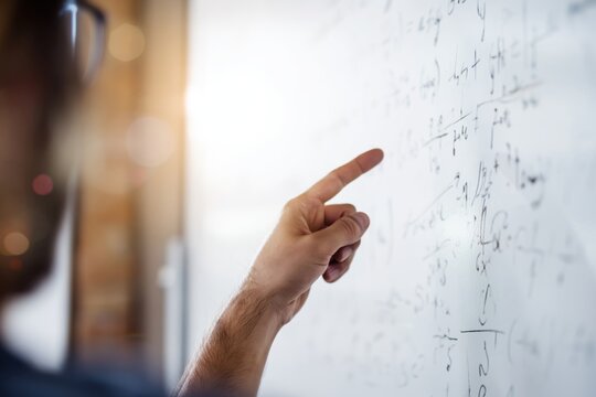 Hand pointing to complex mathematical equations on whiteboard