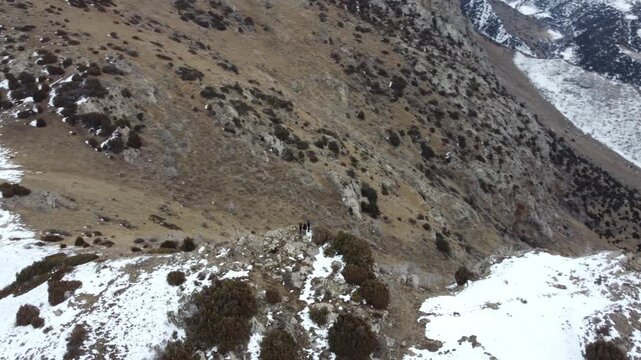 High angle view of hikers on rocky mountain ridge with snow patches, extreme wilderness, Tian Shan, Kazakhstan. High quality 4k footage