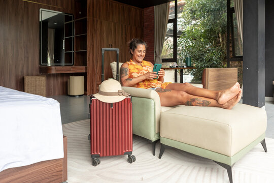 Woman relaxing in hotel room using smartphone on vacation