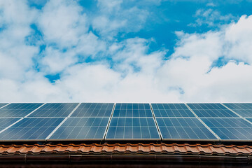 Fototapeta premium Solar panels on a tiled roof under a cloudy sky