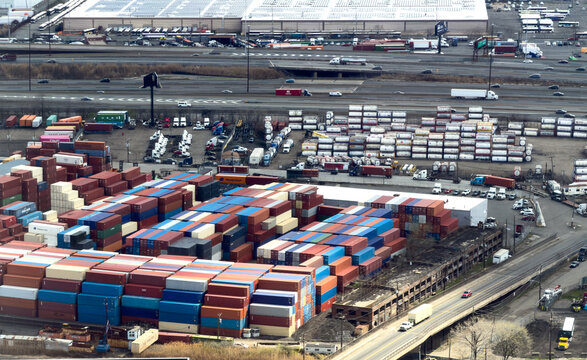 Aerial view of the Port Newark-Elizabeth Marine Terminal featuring rows of stacked intermodal containers and logistics trucks in Elizabeth, New Jersey, United States.