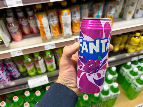 Fanta Grape Soda Can Held in Grocery Store Aisle