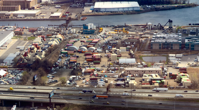Aerial view of the shipping terminal with stacked colorful containers, logistics warehouses, and heavy truck traffic on the highway in Elizabeth, New Jersey, United States.