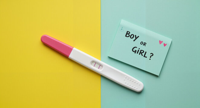 Pregnancy test with card asking 'Boy or Girl?' on colorful background  