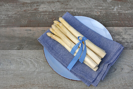 Fresh white asparagus on a blue plate with plenty of space for text.