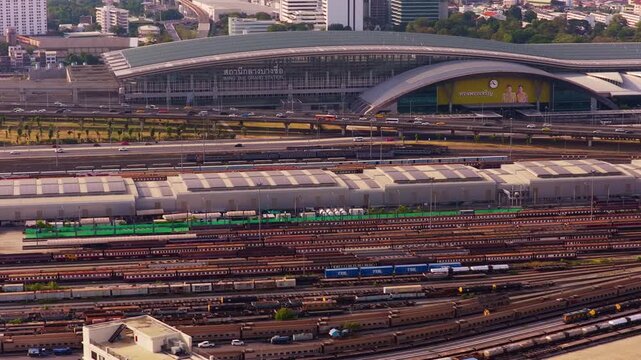 High angle view of Bang Sue Grand Station in Bangkok, Thailand. Busy railway with many trains and tracks, and city highway traffic. Bangkok, Thailand May 2. 2025