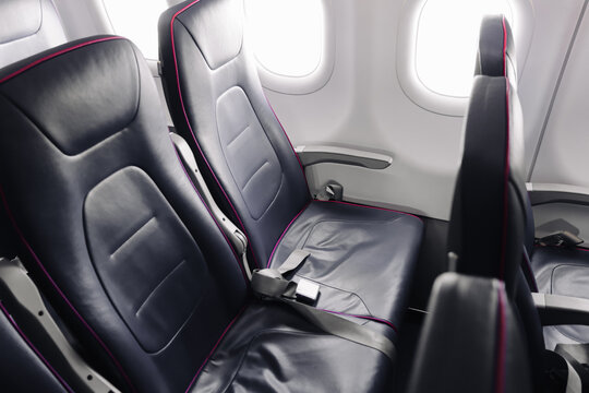 Empty airplane seats in passenger cabin close up. Modern transport interior with safety belts. Travel and aviation concept forming clean minimal background for journey and transport themes.