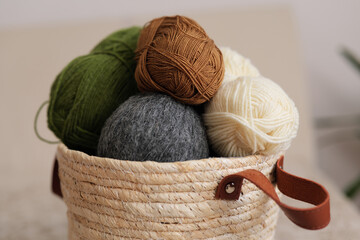 Yarn balls of different colors are placed together in a woven basket. The setting is bright and...