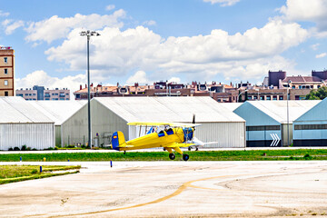 A yellow single-engine biplane waiting to take off at the airfield © Toni