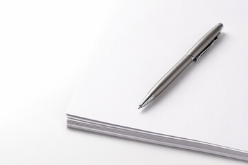 Naklejka premium The Writer's Tool: A modern, elegant pen rests poised on a stack of pristine paper, embodying the essence of creation, ideas, and communication, ready to bring thoughts to life.