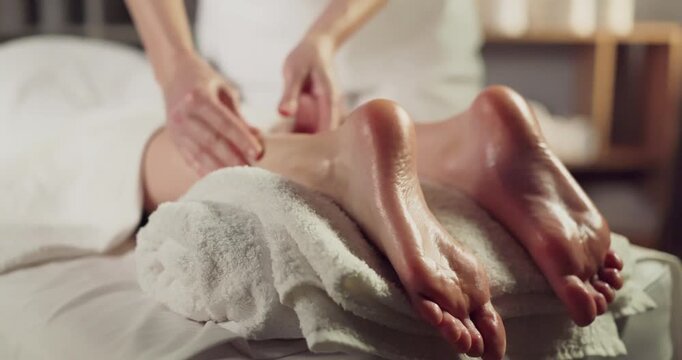 Woman foot massage by therapist hands in spa. Oiled heels and soles are gently pressed to ease tension, closeup on soft towel. Perfect for wellness and beauty uses. Clear concept of wellness care.