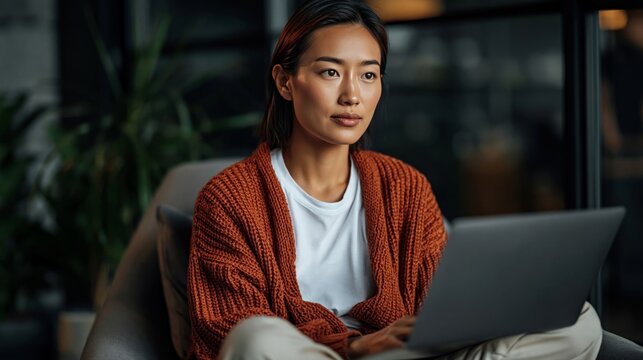 Asian woman working on tablet in modern office. Remote work, digital productivity, and contemporary workplace concept.