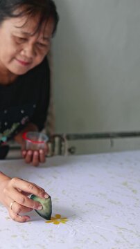 Indonesian woman creating traditional handmade batik pattern