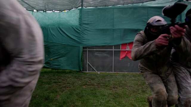 Paintball Player Firing from Cover During Intense Game Combat