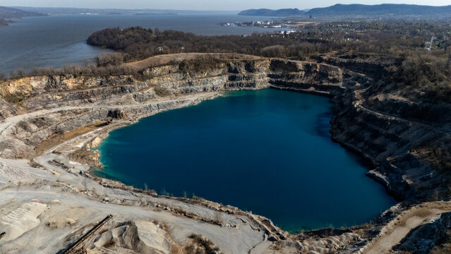 Aerial view of the deep blue water within the tiered stone quarry at Tomkins Cove surrounded by bare trees and hills Stony Point, New York, United States.