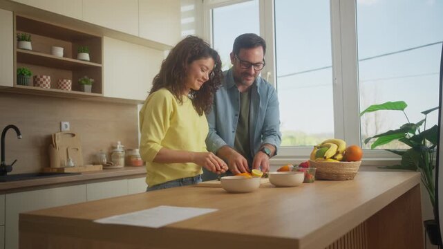 Romantic couple making fruit salad and cutting fruit in cozy kitchen scene