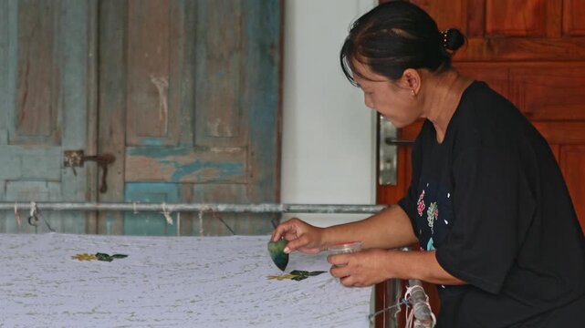 Woman painting a handmade traditional batik fabric