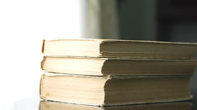 Close up of stacking a pile of old vintage books side view of yellowed paper edges and pages
