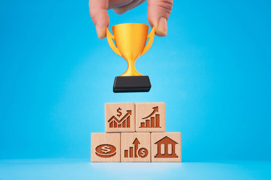 Financial growth concept: hand placing trophy on business pyramid with icons