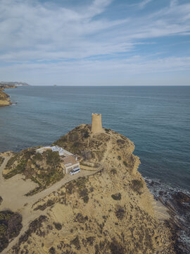 Aerial view of Torre del Xarco on a rocky cliff overlooking the Mediterranean Sea with a small building and a white van nearby La Vila Joiosa, Comunidad Valenciana, Spain.