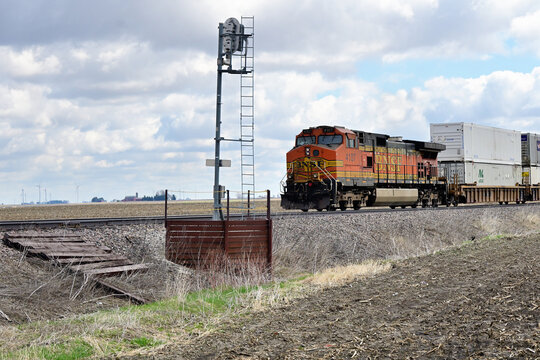 A single locomotive functioning as a rear-train distributed power unit (DPU) clears a signal while helping move a Burlington Northern Santa Fe stack train along a rural stretch of right-of-way.