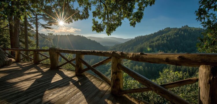 Wooden observation deck with rustic log railing overlooking a vast evergreen forest valley during a bright sunny morning with a prominent sunburst in the sky