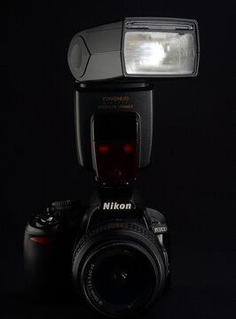 PERPIGNAN, FRANCE - MAY 5, 2026: A Yongnuo speedlight flash mounted on a Nikon D3100 DSLR camera. An example of a budget-friendly photography setup for beginners and enthusiasts.