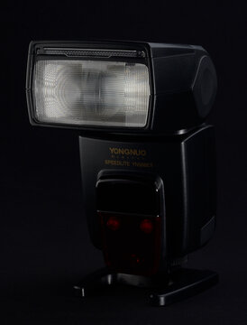 PERPIGNAN, FRANCE - MAY 5, 2026: A close-up shot of a Yongnuo YN-568EX speedlight flash unit on a black background. Professional lighting equipment for DSLR cameras, showing the flash head and control
